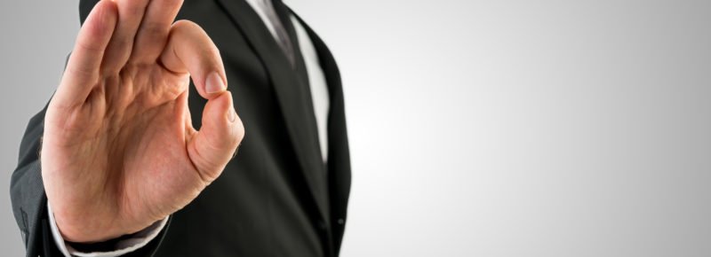 Businessman in Black Coat Showing Okay Hand Gesture. Isolated on Gradient Gray Sky Background.